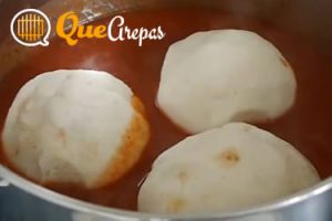 Venezuelan Bollos pelones in a pot with sauce - quearepas.com